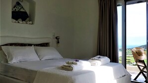 Une chambre avec un grand lit, une vue sur la campagne et un fauteuil près de la fenêtre.