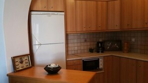 Une cuisine avec des meubles en bois, un réfrigérateur blanc, un four à micro-ondes et une machine à café.