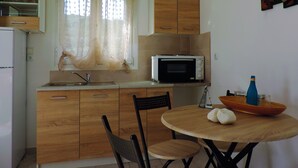 Une cuisine avec des meubles de rangement en bois, un four à micro-ondes, un évier et une table à manger avec des chaises.