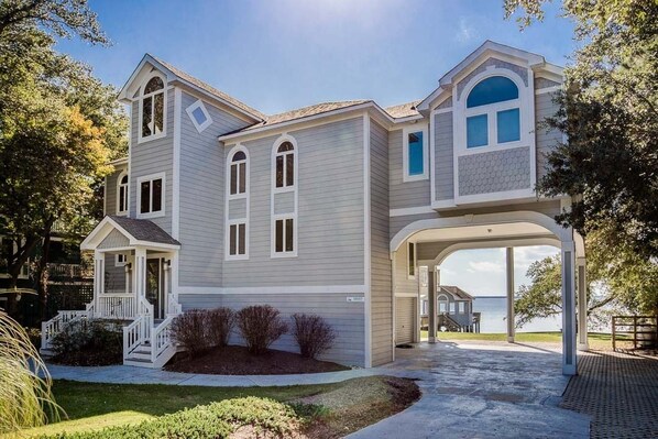 A two-story house with a covered porch and a view of the water.