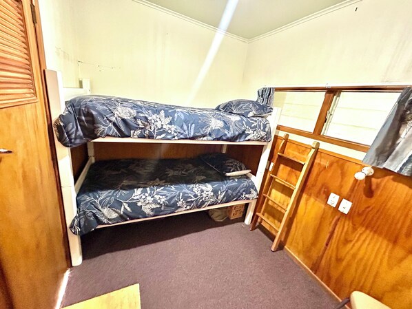 A compact room with a bunk bed, a wooden wardrobe, and a small window. - Crayfish Cove - Unsurpassed Water front location! (Castlepoint)