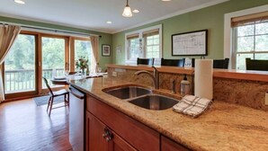 A kitchen with granite countertops, stainless steel sinks, and a wooden dining table. - Charming Cottage in the Village of Warm Springs with Warm Thermal Spring (Warm Springs)