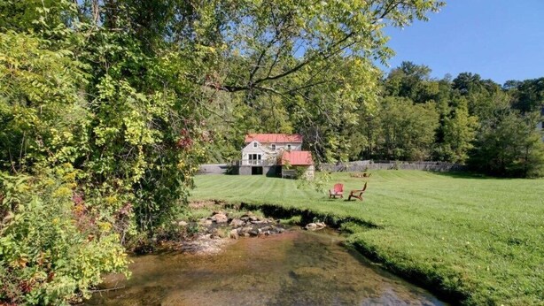 A house with a red roof, surrounded by a well-maintained lawn and a small stream. - Charming Cottage in the Village of Warm Springs with Warm Thermal Spring (Warm Springs)