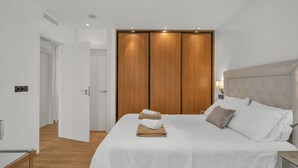 Une chambre à coucher avec un grand lit, une armoire en bois et une table de chevet avec une lampe.