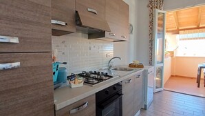 A modern kitchen with wooden cabinets, a gas stove, and a sink. - Il giardino (Piombino)