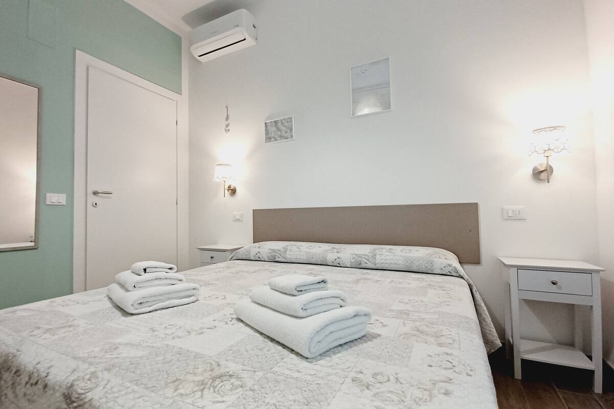 Quarto bem arrumado com uma cama, mesas de cabeceira e um criado-mudo.