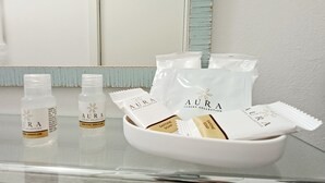 A bathroom counter with toiletries including bottles and soap bars, with a mirror and a light blue wall in the background. - Il giardino (Piombino)