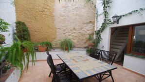A patio with a tiled table and chairs, surrounded by potted plants and a stone wall.