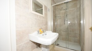 A bathroom with a white sink, a mirror, and a glass-enclosed shower. - Self catering B&B or short holiday let (Saffron Walden)