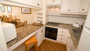 A compact kitchen with white cabinets, a granite countertop, a built-in oven, and a sink. - Holiday Villa with shared pool in Costa Teguise, Las Cucharas (Costa Teguise)