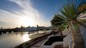 A waterfront view with a calm body of water, a bridge, and a palm tree. - Holiday Villa with shared pool in Costa Teguise, Las Cucharas (Costa Teguise)