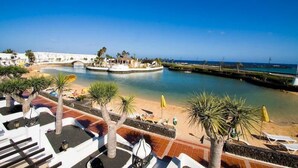 A resort with a pool, beach area, and palm trees. - Holiday Villa with shared pool in Costa Teguise, Las Cucharas (Costa Teguise)
