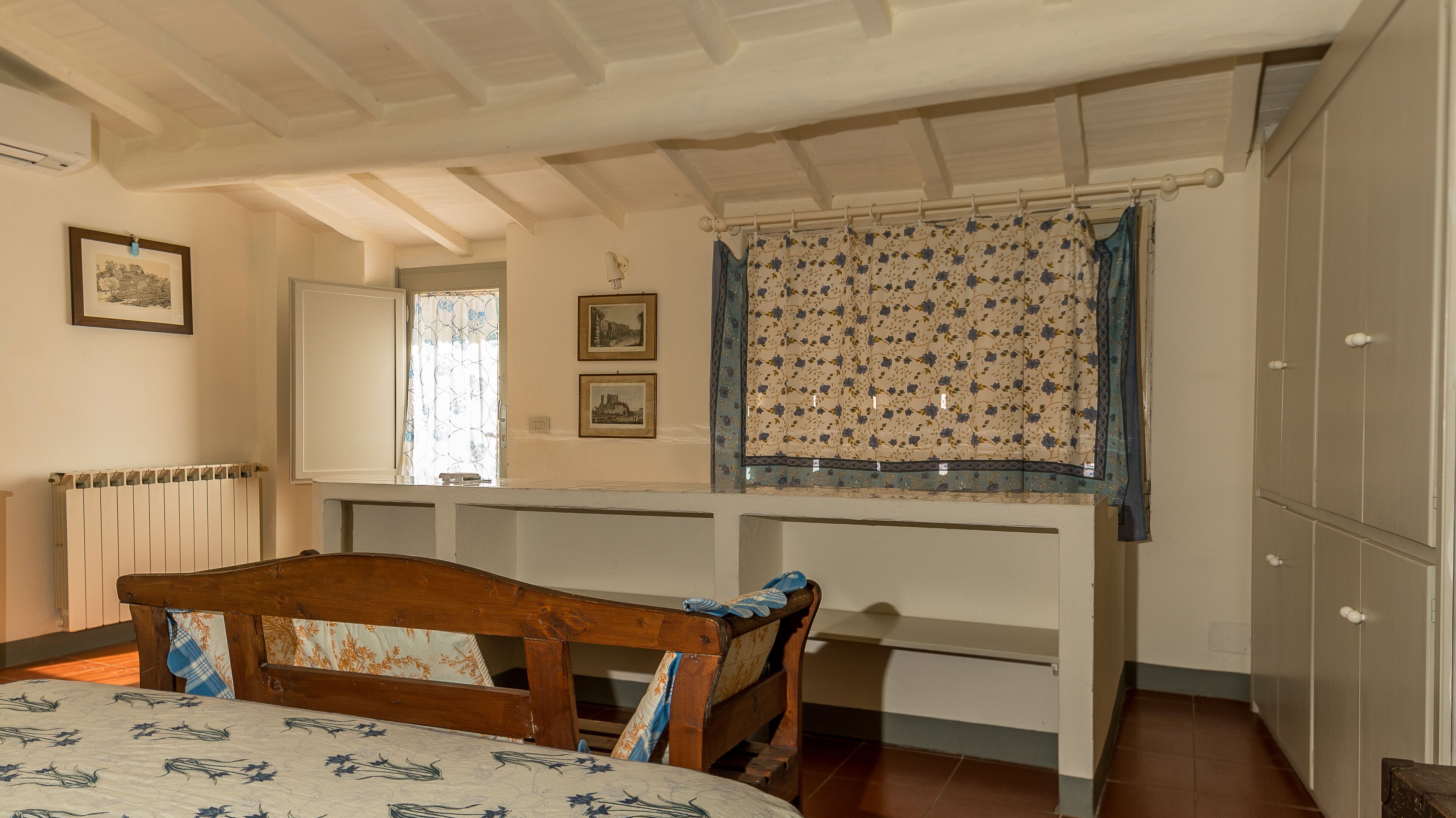 Un dormitorio con una cama de madera, una ventana con cortinas florales y un radiador.