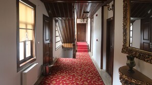 Un couloir avec un tapis rouge, des portes en bois et un grand miroir décoratif.