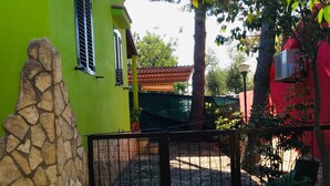 A green building with a stone wall, a metal gate, and a paved walkway.