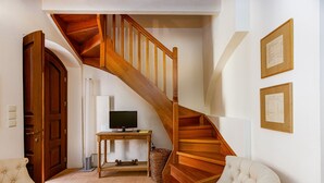 A staircase with wooden railings, a television on a stand, a wicker basket, and two upholstered chairs. - Charming Venetian house in heart of Rethymno (Rethymno)