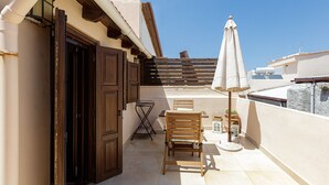 A balcony with a wooden chair, a small table, a potted plant, and an umbrella. - Charming Venetian house in heart of Rethymno (Rethymno)