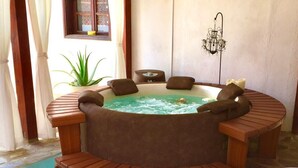 Un bain à remous avec des bancs en bois et un sol en pierre.