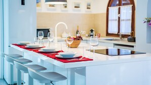 Une cuisine moderne dotée d’un îlot central, de tabourets de bar, de luminaires suspendus et offrant une vue sur l’espace repas.