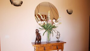 Ein Konsolentisch aus Holz mit Blumen in einer Vase, einer dekorativen Elefantfigur und einem wandmontierten Spiegel.