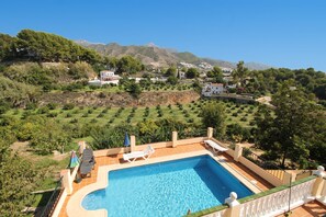A swimming pool with lounge chairs and a view of a hillside village.