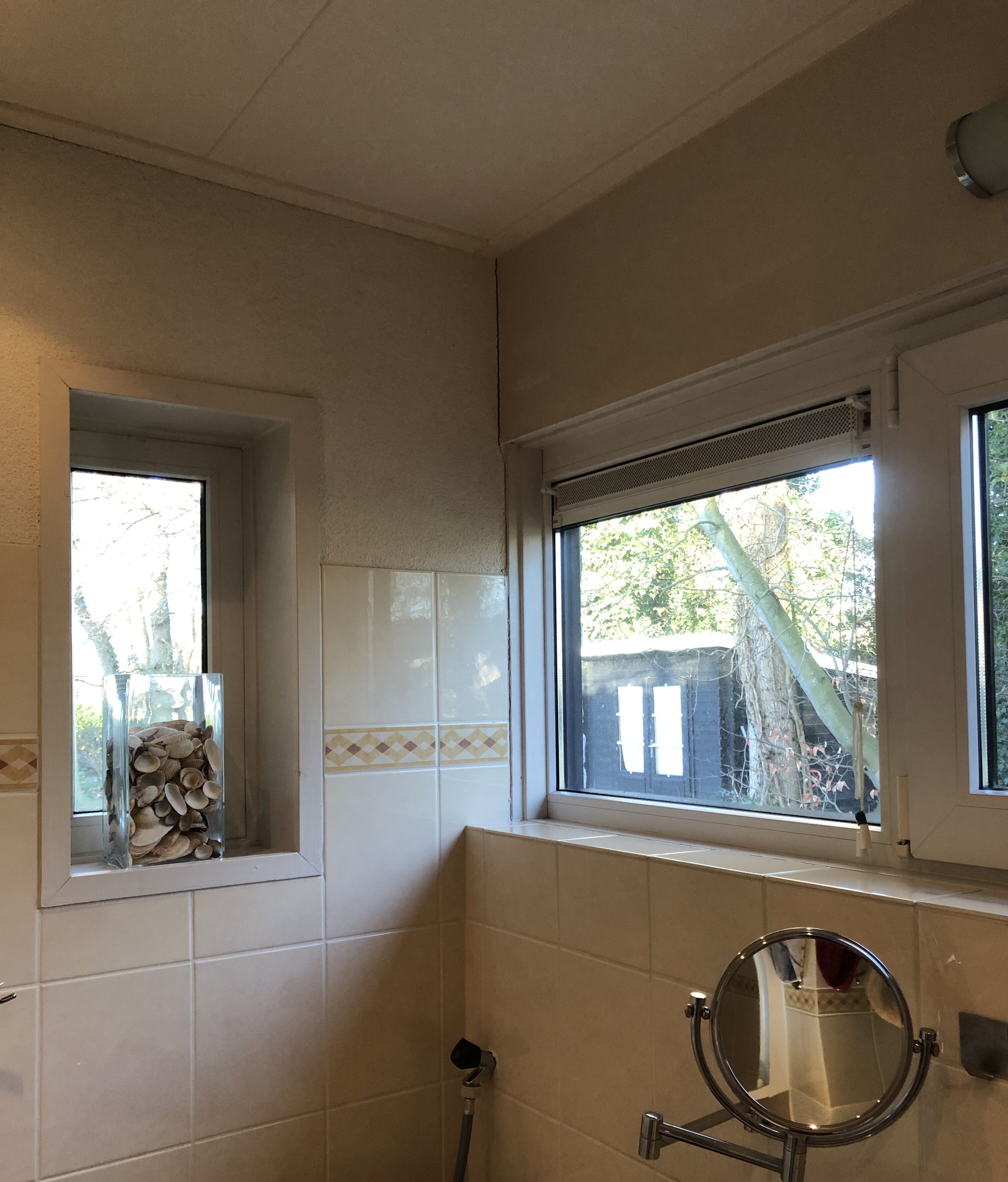 Une salle de bain avec une fenêtre, un miroir et un porte-serviettes.
