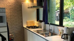 Een moderne keuken met een gasfornuis, een roestvrijstalen spoelbak en een koffiezetapparaat.