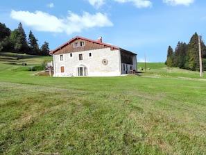 A stone building with a red roof, a door, and windows. - Homerez - House in Septmoncel (Septmoncel)