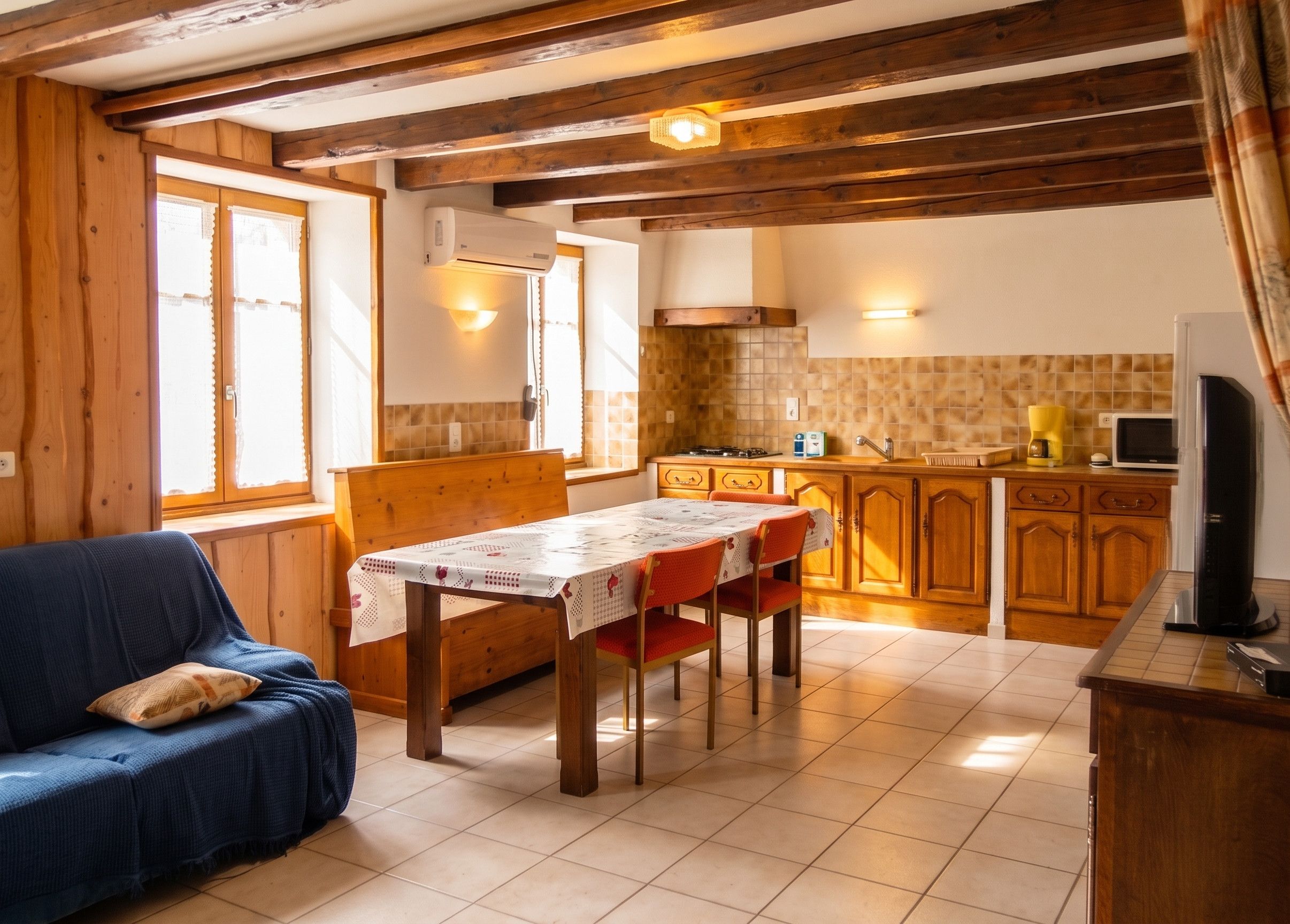 A cozy room with a dining table, wooden cabinets, and a television.