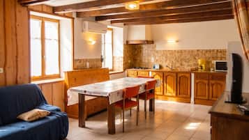 A cozy room with a dining table, wooden cabinets, and a television.