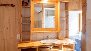 Ein Badezimmer aus Holz mit einem großen Spiegel, einem Waschbecken und einem Handtuchhalter.