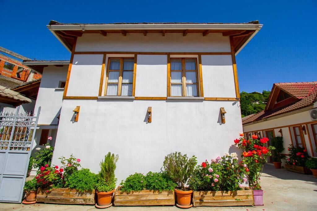 Un edificio tradicional de dos pisos con fachada blanca y marcos de madera para las ventanas.
