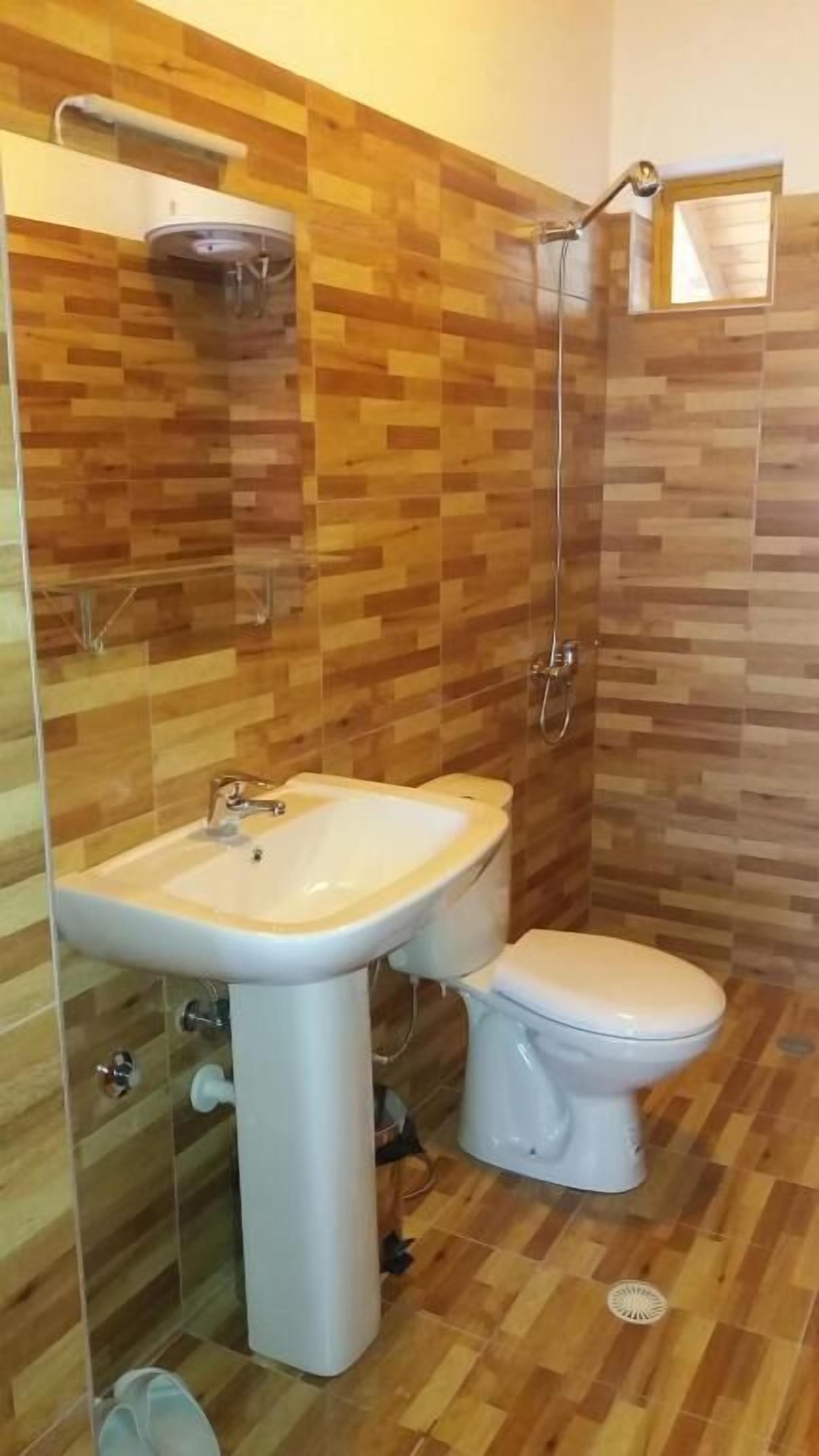 Un baño con suelo de madera, un lavabo blanco y un inodoro.