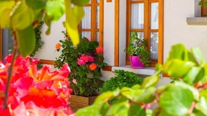 Una casa con ventanas de madera, un porche y plantas en macetas.