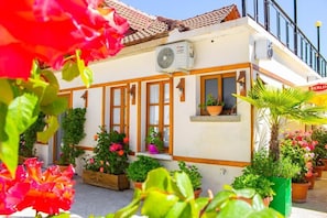 A building with a white facade, wooden window frames, and a tiled roof. - Hotel Bebej Tradicional (Gjirokastër)