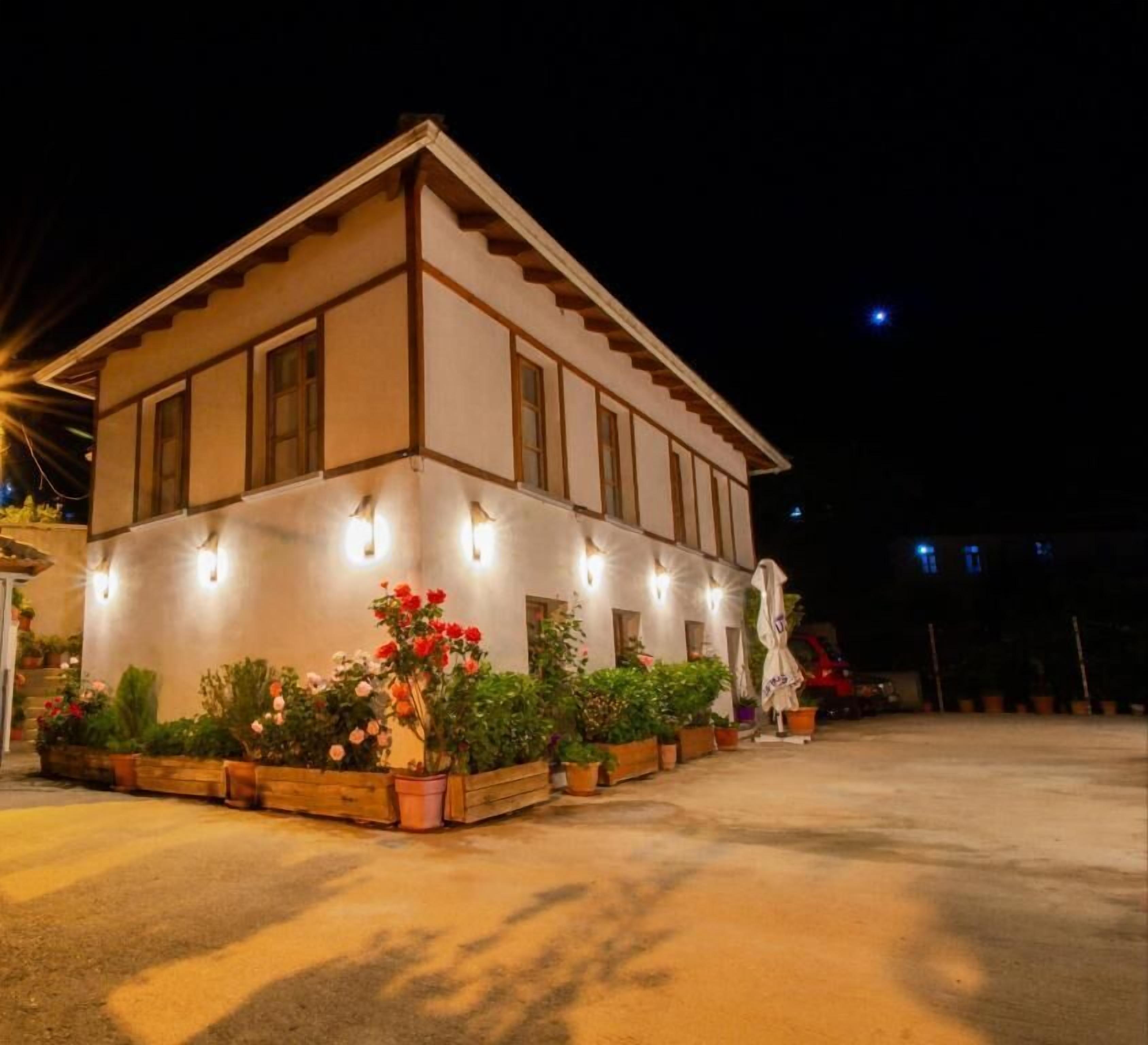 Un edificio de dos plantas con fachada simétrica, iluminado con luces exteriores.