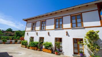 Un edificio bianco con infissi in legno e numerosi balconi, circondato da piante in vaso.