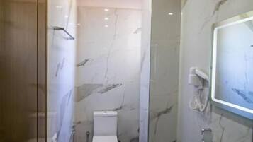 Un baño con inodoro, lavabo y zona de ducha.