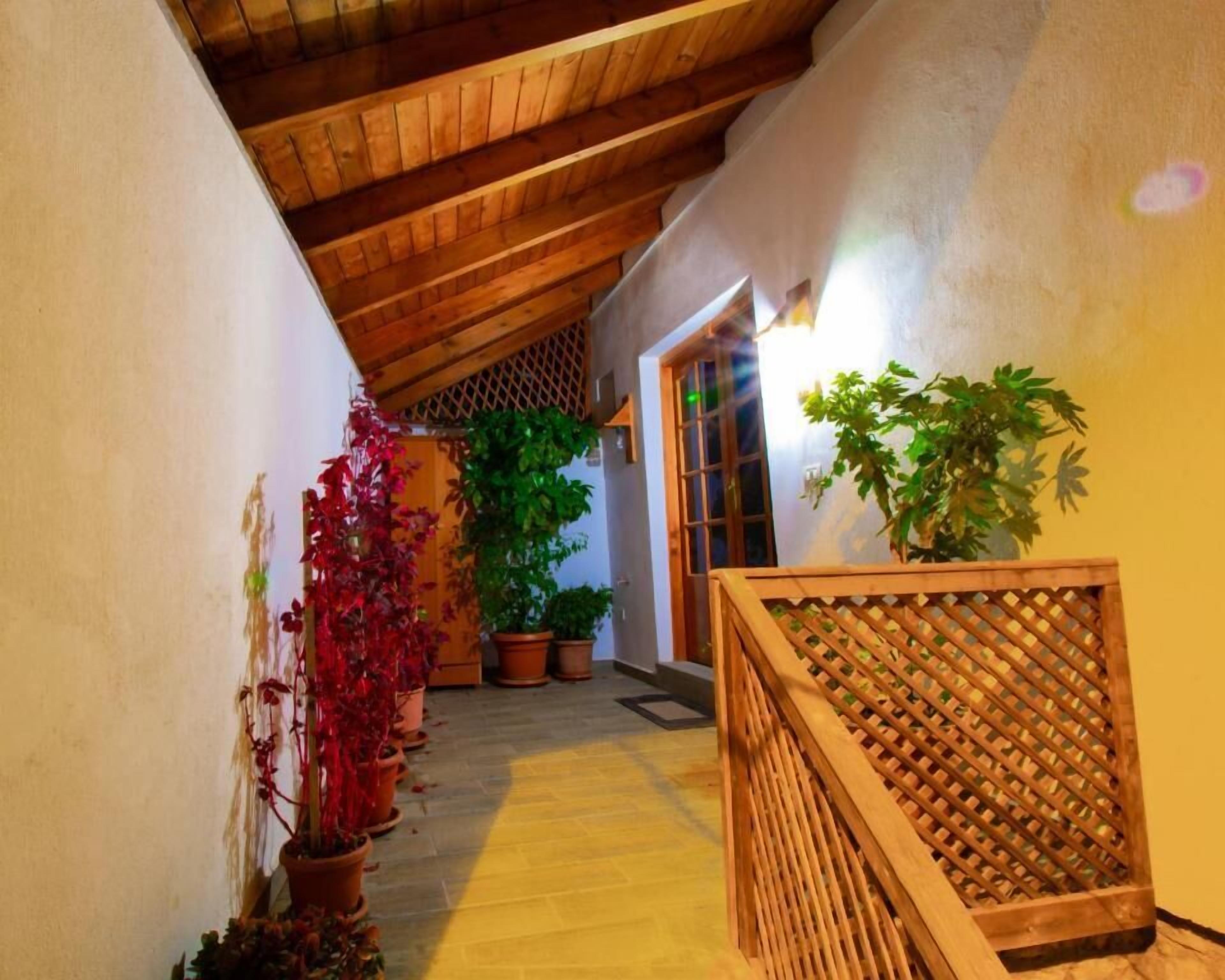 A narrow hallway with wooden ceiling beams, potted plants, and a wooden lattice partition.