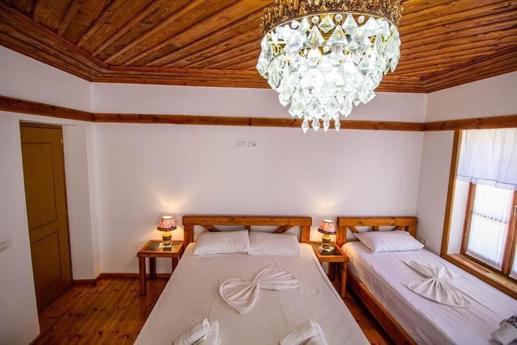Une chambre d’hôtel avec un plafond en bois, un lustre, deux lits avec des serviettes et des lampes de chevet.