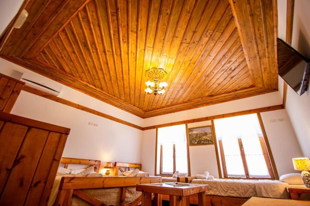 Een gezellige kamer met houten balkenplafond, een bed met hoofdeinde, een tafel en een raam met een schilderij.