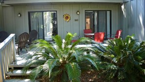 A covered patio with outdoor seating, palm trees, and a decorative sun on the wall. - Spacious Villa Lovely golf course view Free Tennis-PB! 20% Aug 29! (Hilton Head Island)