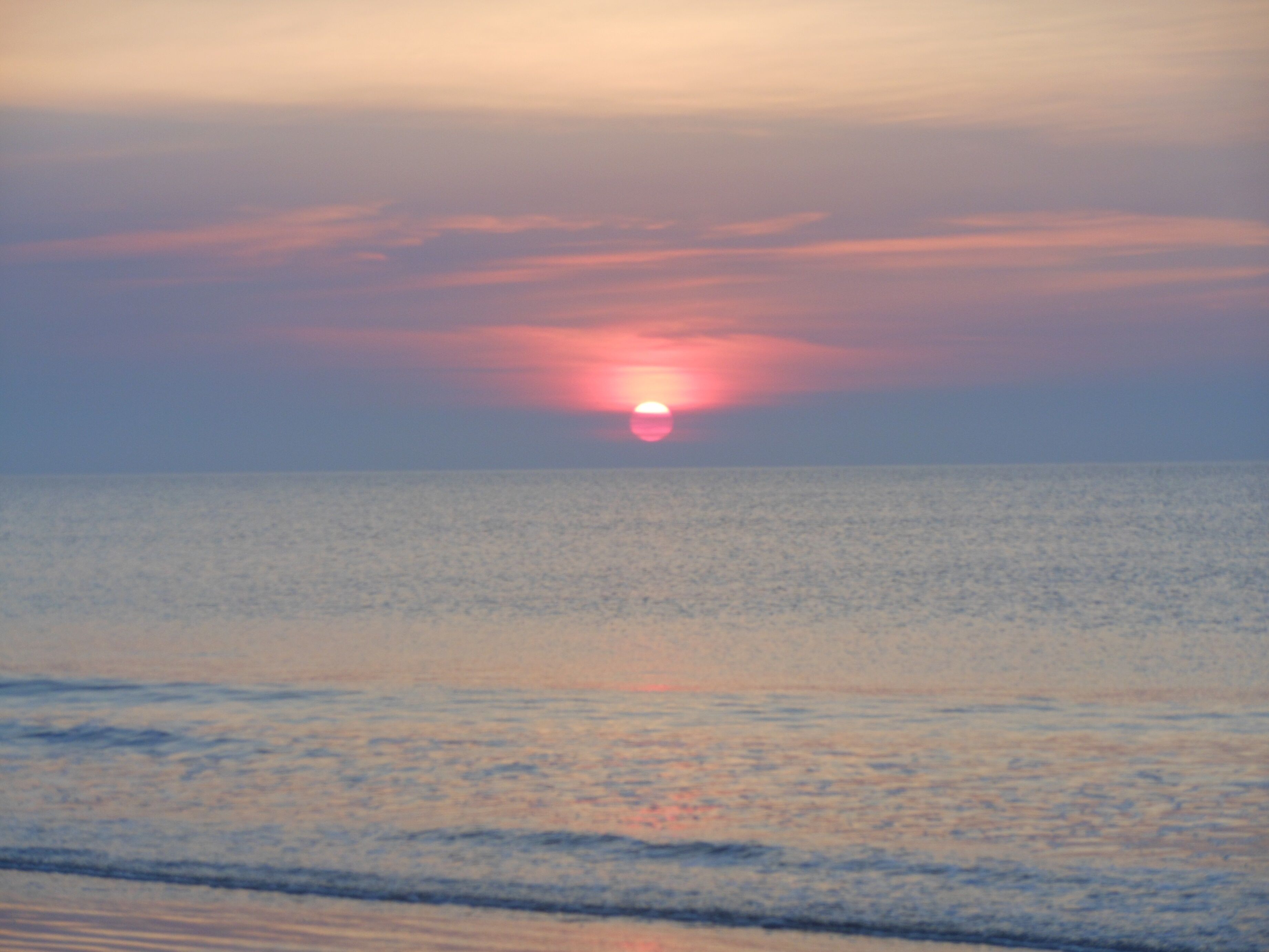 A sunset over a calm sea with a clear horizon.