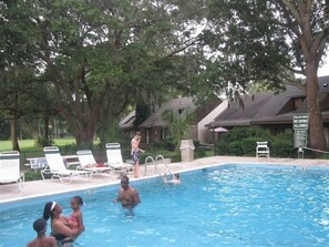 Relax by the pool surrounded by lush greenery and comfortable lounge chairs.