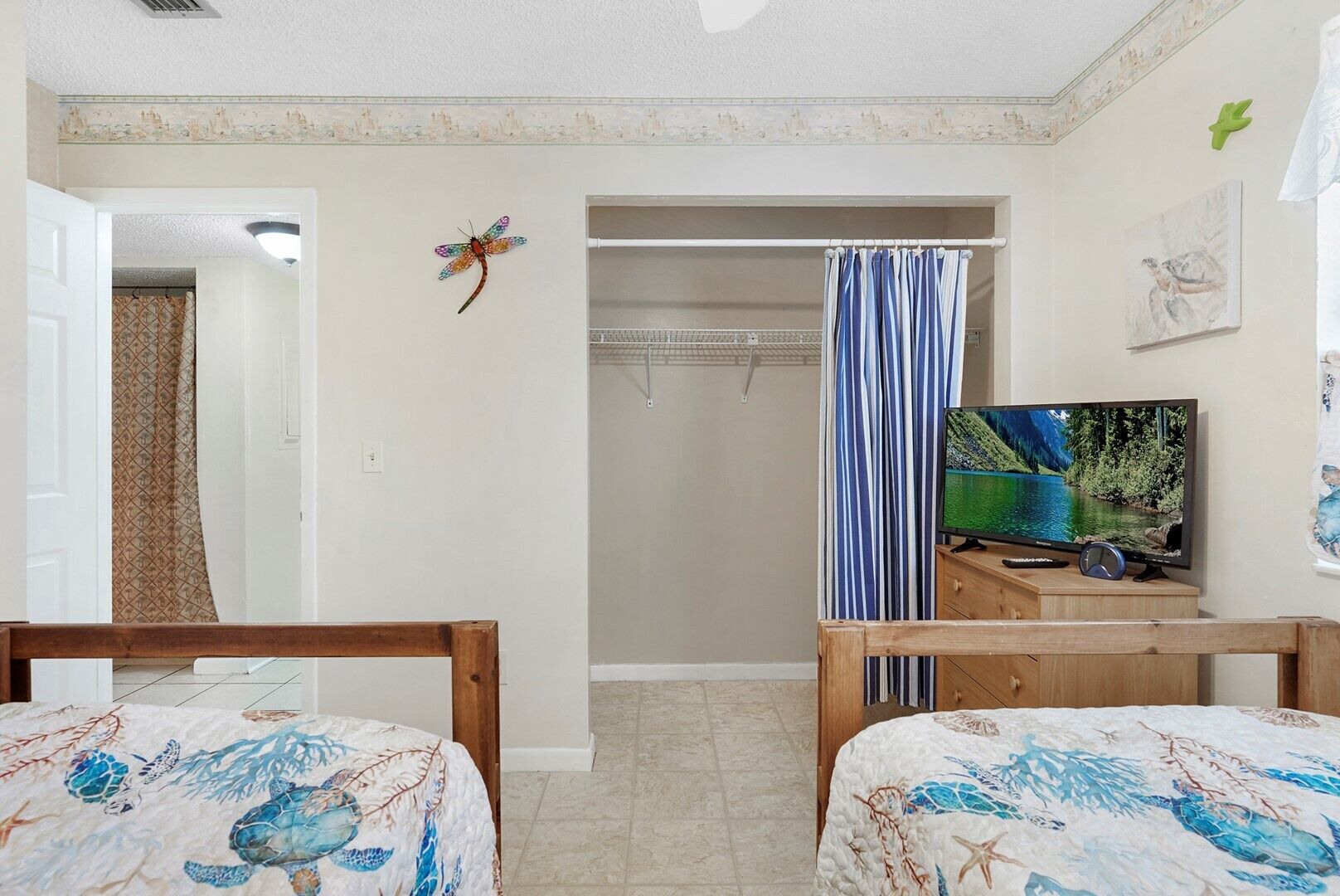 A bedroom with two wooden beds, a television, a shower curtain, and a door leading to another room.