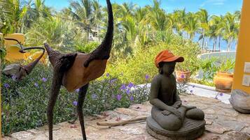 Una estatua de un árbol con tronco curvo y una figura sentada con sombrero sobre una plataforma de piedra.