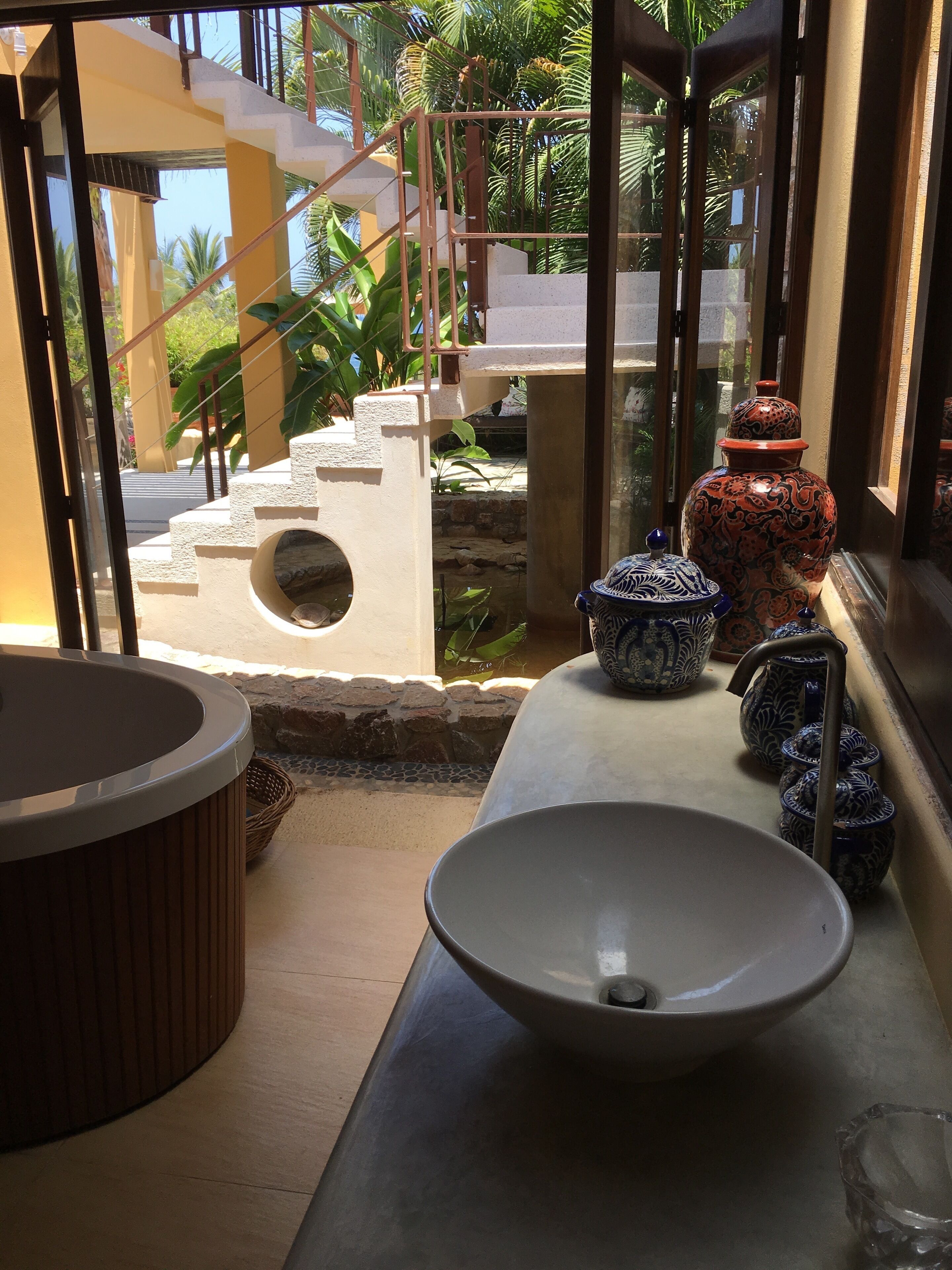 Un baño con un lavabo grande, una bañera y jarrones decorativos.