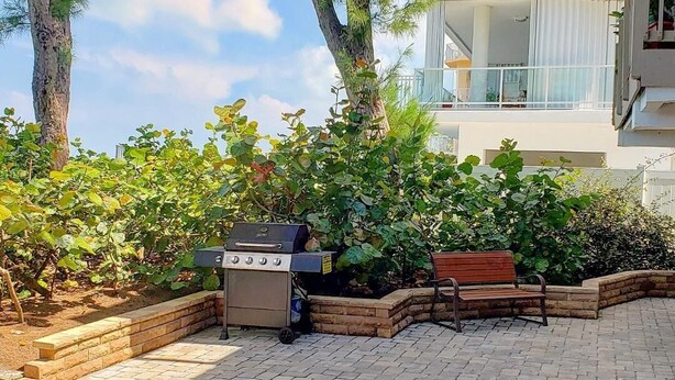 Un patio con una parrilla, un banco y vistas a un edificio de varios pisos.