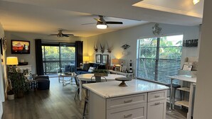 Una cocina moderna con una isla central, zona de comedor y un rincón acogedor con televisión.