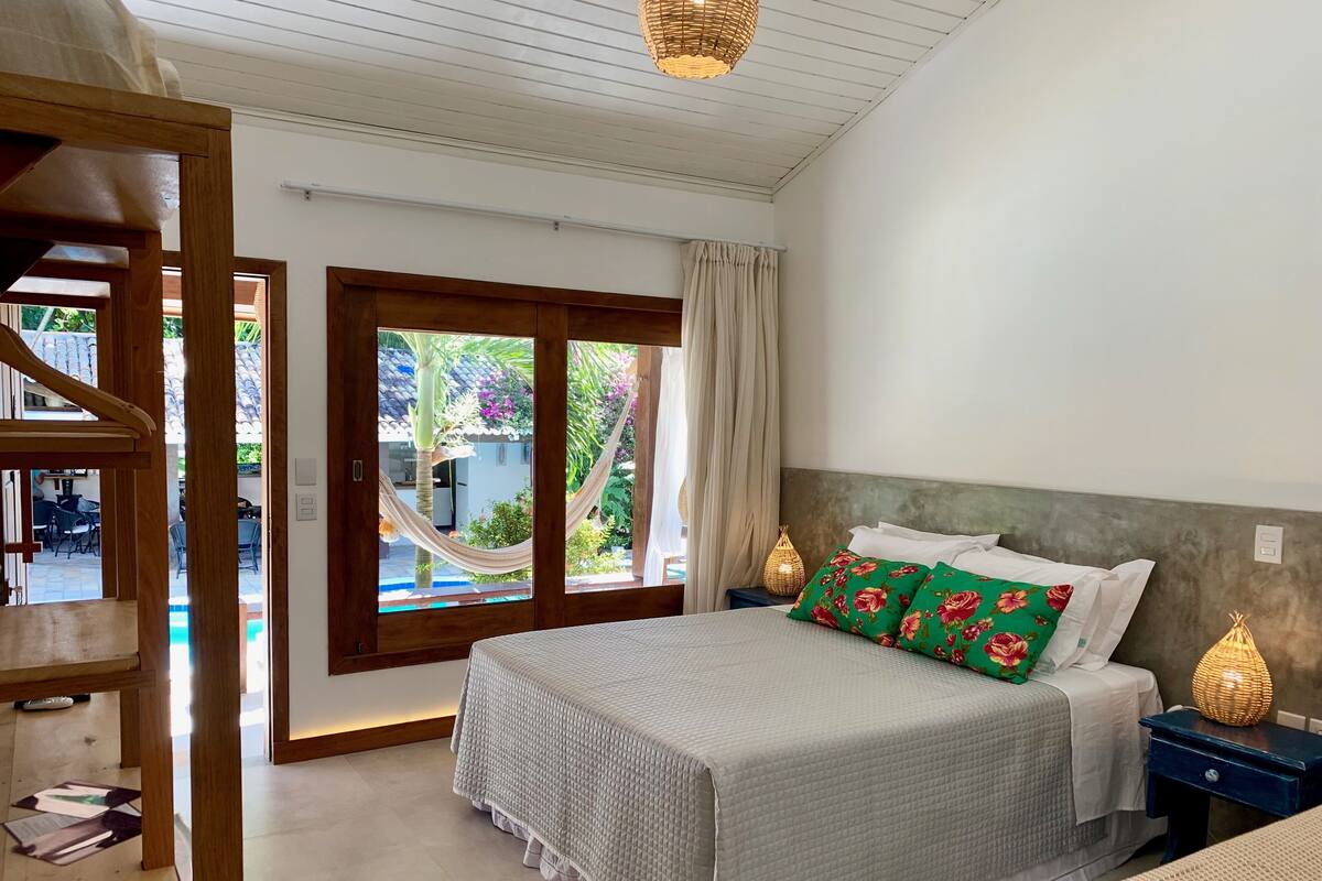A bedroom with a bed, nightstands, and a view of the outside.